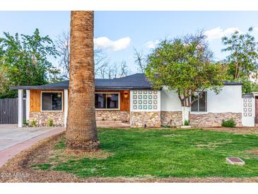 Charming single-story home with a well-maintained lawn, rock accents, and mature palm trees at 4333 N 15Th Dr, Phoenix, AZ 85015