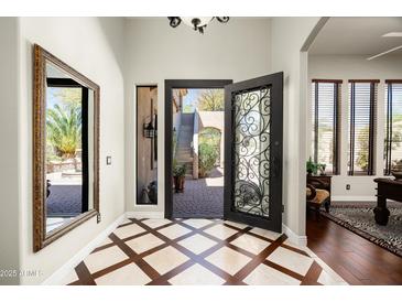 Elegant foyer featuring custom tile flooring, decorative iron door, and a view to the outdoor courtyard at 21235 N 80Th Way, Scottsdale, AZ 85255