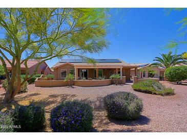 View of the backyard with desert landscaping, covered patio, and solar panels at 3147 N Couples Dr, Goodyear, AZ 85395