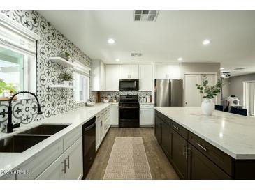 Modern kitchen featuring white cabinets, stainless steel appliances, decorative backsplash and spacious countertops at 8115 E Cypress St, Scottsdale, AZ 85257