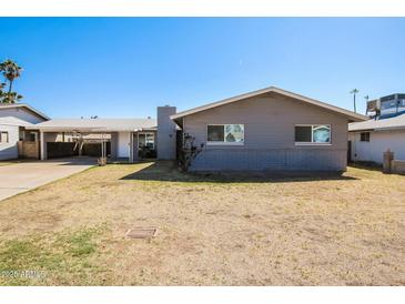 Charming single-story home with a carport and a well-maintained front yard under a clear blue sky at 1055 W Dragoon Ave, Mesa, AZ 85210