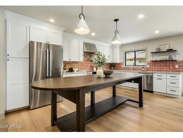 Bright kitchen features stainless steel appliances, white cabinets, large island, and decorative tile backsplash at 8361 E Via De Viva --, Scottsdale, AZ 85258