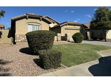 Charming single-story home with desert landscaping, stone accents and a two-car garage on a sunny day at 11570 W Pima St, Avondale, AZ 85323