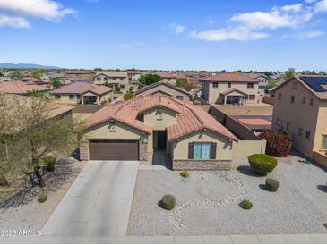 Attractive single-story home featuring a tile roof, neutral stucco, a two-car garage, and desert landscaping at 16438 W Buchanan St, Goodyear, AZ 85338