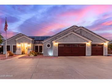Charming home with a two-car garage, desert landscaping, and a welcoming entrance, illuminated by soft exterior lights at 23040 W Hammond Ln, Buckeye, AZ 85326