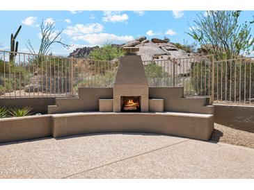 An outdoor fireplace with seating and desert views offers a cozy spot for relaxation and entertainment at 11451 E Christmas Cholla Dr, Scottsdale, AZ 85255