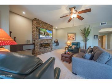 Comfortable living room features a stunning stone fireplace and modern ceiling fan at 19700 N 76Th St # 2091, Scottsdale, AZ 85255