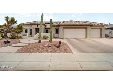 Desert landscaping accents this home featuring a tile roof and three-car garage at 20017 N Cielo Ct, Surprise, AZ 85374