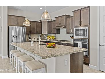 Well-equipped kitchen featuring granite countertops, island with seating, and stainless appliances at 30406 N 116Th Ln, Peoria, AZ 85383