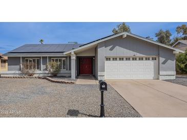 Charming single-story home with a red door, solar panels, and a well-maintained front yard at 514 E Barrus Pl, Casa Grande, AZ 85122