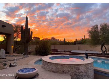 Backyard pool and spa with desert landscaping set against a vibrant sunset sky at 8625 E Camino Vivaz --, Scottsdale, AZ 85255