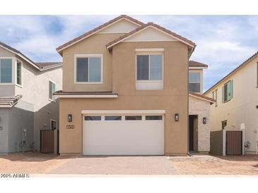 Two-story home featuring a two-car garage, tan stucco, and manicured landscaping at 1565 E Tiffany Way, Gilbert, AZ 85298