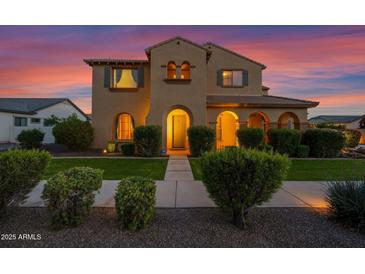 Inviting two-story home featuring a well-manicured lawn and a classic stucco exterior illuminated by a vibrant sunset at 21525 E Camacho Rd, Queen Creek, AZ 85142