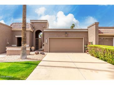 Charming home with a gated entry, brown garage door, desert landscaping, and a beautiful blue sky at 25238 S Mohawk Dr, Sun Lakes, AZ 85248