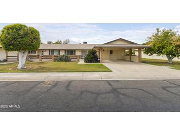 Charming single-story home with a well-manicured lawn and covered carport at 10927 W Peoria Ave, Sun City, AZ 85351