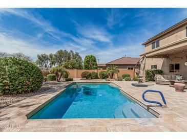 Backyard oasis featuring a sparkling pool, lush landscaping, and a covered patio for ultimate relaxation at 26011 W Tonopah Dr, Buckeye, AZ 85396