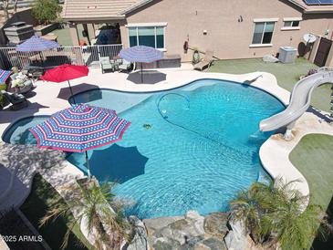 Aerial view of a sparkling private backyard pool with a slide, diving board, water feature, and patio at 16511 W Cortez St, Surprise, AZ 85388