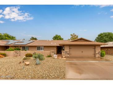 Single-story home featuring a desert rock yard, covered porch, and a two-car garage at 18211 N Conestoga Dr, Sun City, AZ 85373