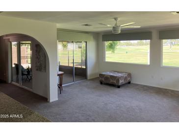 Bright living room offering golf course views from large windows and sliding doors to the enclosed patio at 18211 N Conestoga Dr, Sun City, AZ 85373