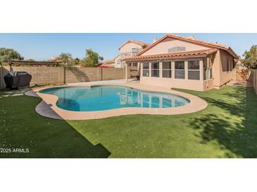 Sparkling private pool surrounded by artificial grass and block fence, creating a serene outdoor oasis at 19412 N 77Th Ave, Glendale, AZ 85308