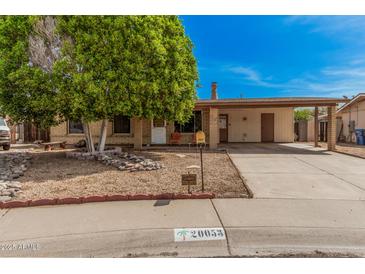 Charming brick home featuring a large tree, covered parking, and desert landscaping at 20053 N 15Th Dr, Phoenix, AZ 85027