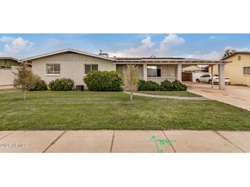 Charming single-story home featuring a well-manicured lawn, fresh landscaping, and a covered carport at 299 N Comanche Dr, Chandler, AZ 85224