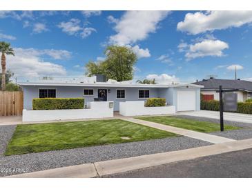 Charming single-story home features a manicured front yard and a lovely, light blue painted facade at 4907 E Piccadilly Rd, Phoenix, AZ 85018