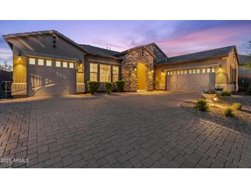 Stunning home featuring a stone archway, three-car garage, and brick driveway under a picturesque twilight sky at 10778 N 137Th St, Scottsdale, AZ 85259
