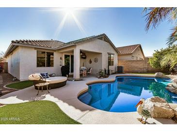 Backyard pool with a covered patio, lounge seating, and palm trees, perfect for outdoor relaxation at 17704 W Tasha Dr, Surprise, AZ 85388