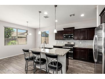 Modern kitchen with granite counters, stainless steel appliances, dark cabinetry, and an island with seating at 4253 E Palo Verde St, Gilbert, AZ 85296