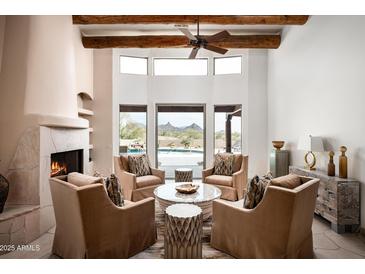 Bright living room with fireplace, wood beam ceiling, and views of the outdoor pool and desert landscape at 8400 E Dixileta Dr # 153, Scottsdale, AZ 85266