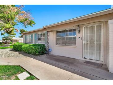 Charming single-story home featuring manicured landscaping, security door, and beautiful mature shade tree at 903 N Revere St # F, Mesa, AZ 85201