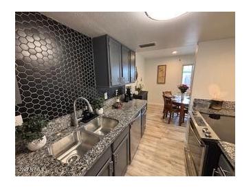 Modern kitchen featuring granite countertops, stainless steel appliances, and stylish backsplash at 948 S Alma School Rd # 115, Mesa, AZ 85210