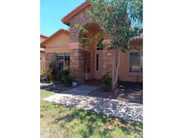 Charming single story home with an arched stone entryway and well maintained front yard at 11233 W Olive Dr, Avondale, AZ 85392