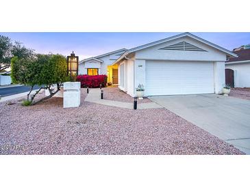 Charming single-story home with two-car garage, xeriscape landscape, and inviting entryway with mature landscaping at 614 W Kings Ave, Phoenix, AZ 85023