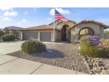 Charming single-story home with a well-kept yard, desert landscaping, and an American flag at 9954 W Mohawk Ln, Peoria, AZ 85382