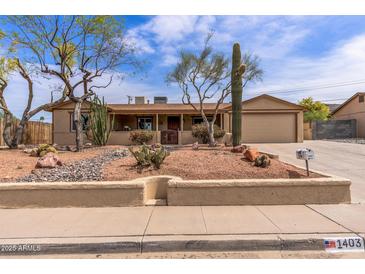 Charming single-story home featuring desert landscaping, a two-car garage, and a covered front porch at 1403 W Wood Dr, Phoenix, AZ 85029