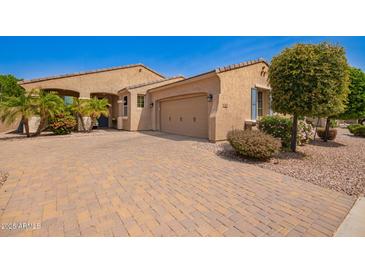 Charming single-story home featuring desert landscaping, a brick driveway, and an attached two-car garage at 14390 W Desert Flower Dr, Goodyear, AZ 85395
