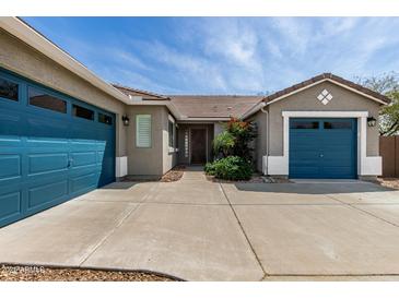 Inviting front entrance with a three-car garage, desert plants, and covered walkway leading to front door at 23063 W Loma Linda Blvd, Buckeye, AZ 85326