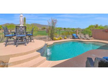 Stunning backyard pool with waterfall feature, seating and beautiful desert golf course views at 2452 W Muirfield Dr, Anthem, AZ 85086