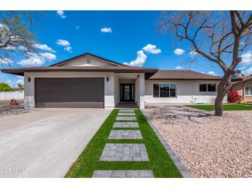 Charming single-story home featuring a manicured lawn and driveway leading to an attached two-car garage at 8602 E Whitton Ave, Scottsdale, AZ 85251