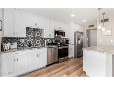 Modern kitchen with white cabinets, stainless steel appliances, granite countertops, and decorative backsplash at 17822 N Del Webb Blvd, Sun City, AZ 85373