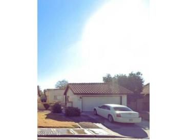 Charming single-story home with a well-maintained front yard and a private driveway with a white car at 2221 E Florian Ave, Mesa, AZ 85204