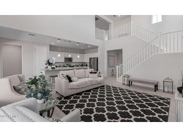 Bright living room featuring an open floor plan, modern staircase, and access to the kitchen at 2377 S 245Th Dr, Buckeye, AZ 85326