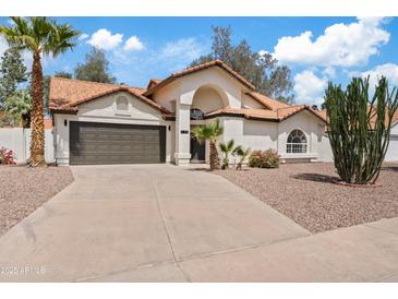 Inviting single-story home with a well-manicured front yard and a two car garage, surrounded by mature desert landscaping at 438 E Hackamore St, Mesa, AZ 85203