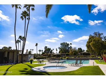 Resort-style pool area with palm trees and lounge chairs against a bright blue sky at 4800 N 68Th St # 314, Scottsdale, AZ 85251