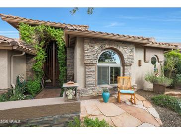 Charming home featuring a stone facade, arched window, and covered front porch with a cozy rocking chair at 7517 E Mariposa Grande Dr, Scottsdale, AZ 85255