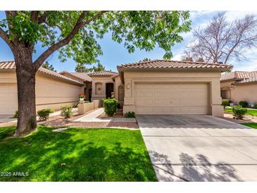 Charming single-story home boasts lush front lawn, mature tree, and a two-car garage at 9717 E Holiday Way, Sun Lakes, AZ 85248