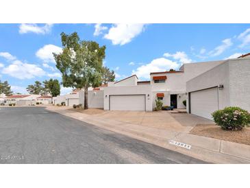 View of a charming white stucco home with a spacious two-car garage and well-maintained landscaping at 13811 N 42Nd Pl, Phoenix, AZ 85032