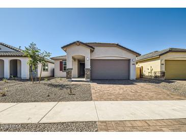 Charming single-story home with a brick driveway, neutral stucco, and a well-manicured desert landscape at 15585 W Williams St, Goodyear, AZ 85338